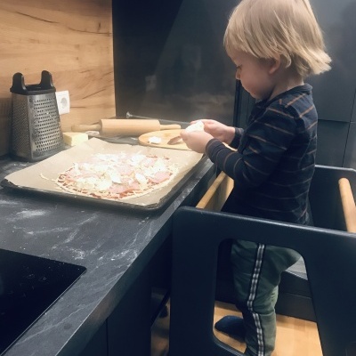 Criança a preparar pizza numa cozinha moderna