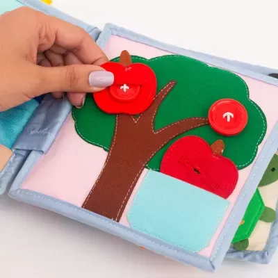 Livro de tecido com atividades e maçãs com botões em árvore