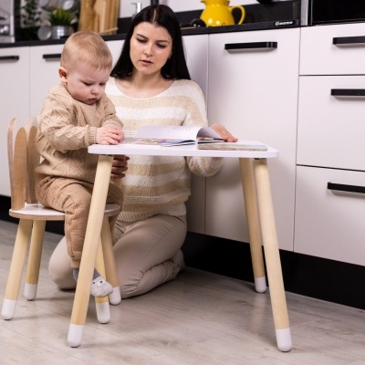 Mesa e cadeira infantis de madeira clara com detalhes brancos numa cozinha moderna