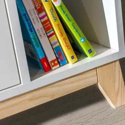 Móvel branco com pés de madeira clara e livros coloridos numa prateleira.