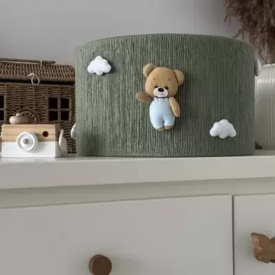 Caixa organizadora redonda verde com decoração de ursinho e nuvens em cómoda branca