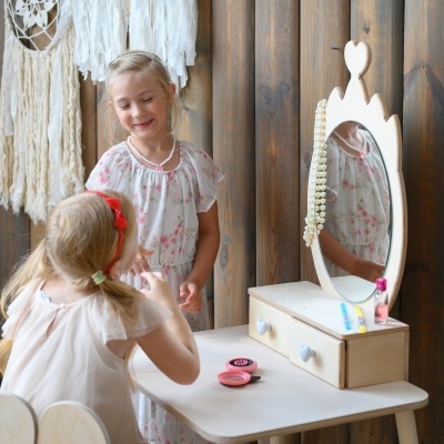 Mesa branca com espelho oval e duas meninas a brincar