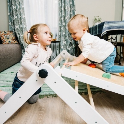 Crianças a brincar numa escada de madeira branca com degraus coloridos na sala