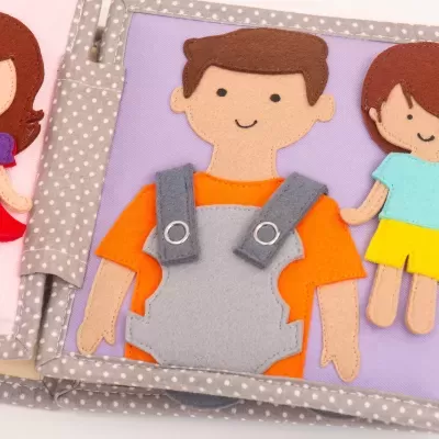 Livro infantil de tecido com três bonecos de feltro coloridos