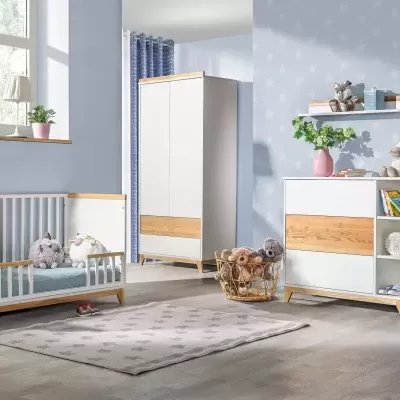 Quarto infantil com móveis brancos e detalhes em madeira clara, decoração azul e brinquedos de peluche.