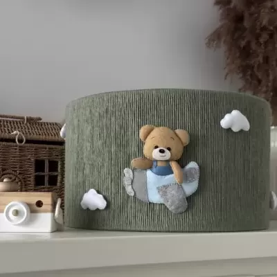 Cesta verde com ursinho de pelúcia a voar e nuvens, em prateleira branca