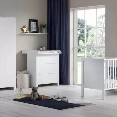 Quarto de bebé com móveis brancos, berço, cómoda muda-fraldas, armário, tapete, brinquedos e decoração