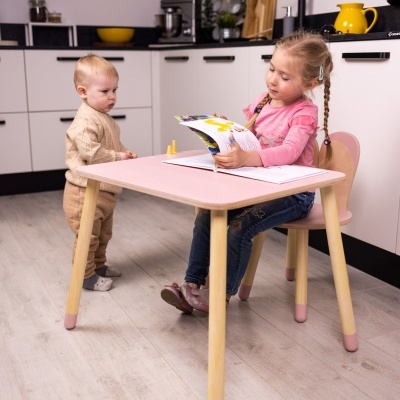 Mesa infantil quadrada rosa com pernas de madeira numa cozinha