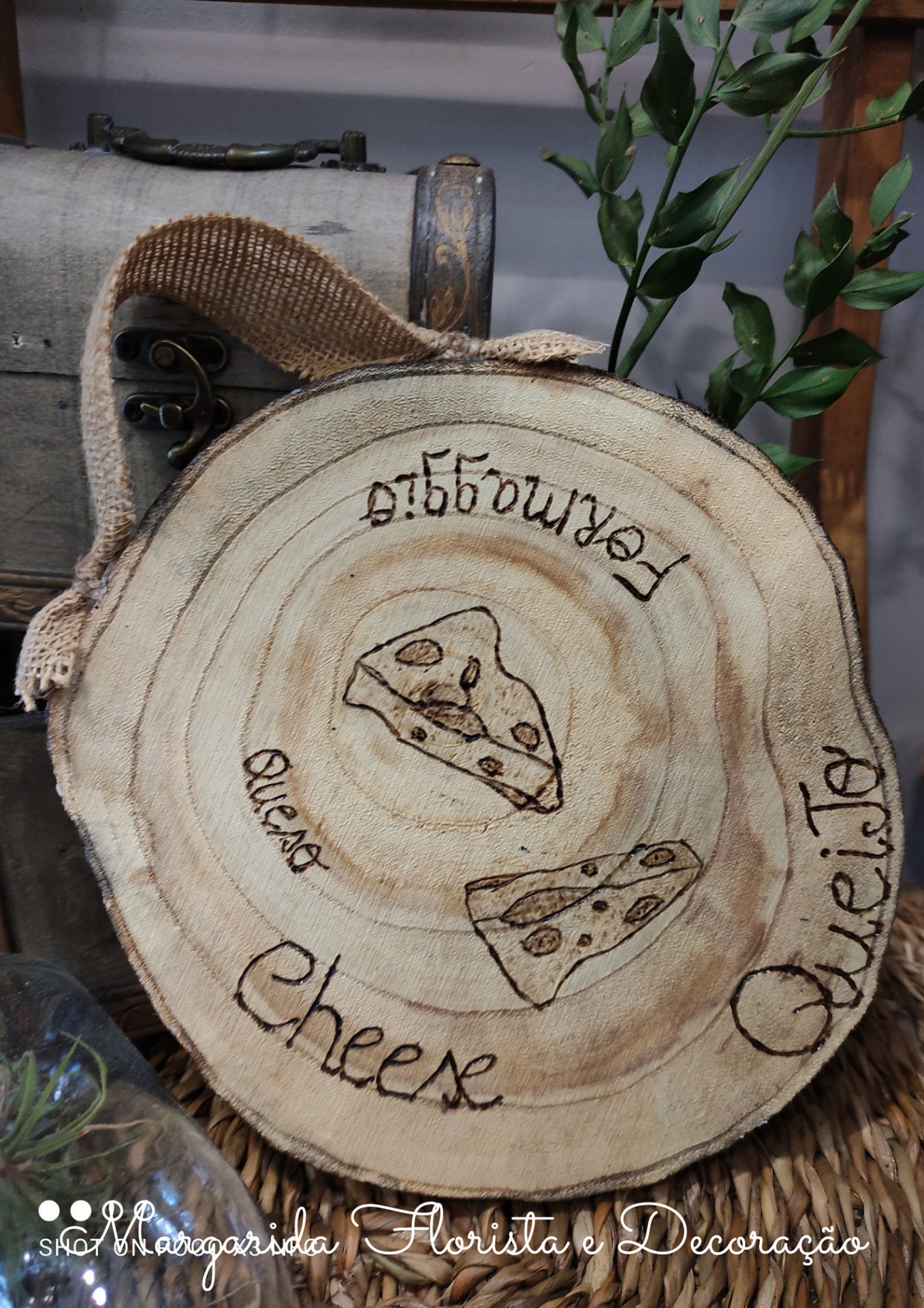 Disco de madeira decorativo com desenhos de queijo e palavras em várias línguas