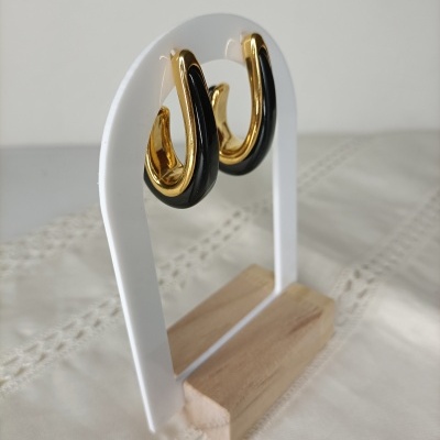 Brincos dourados e pretos meia argola em estrutura branca com base de madeira