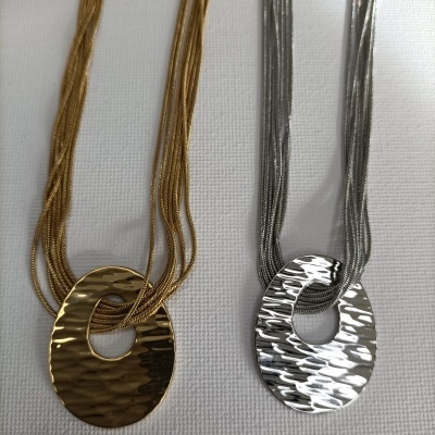 Dois colares, um dourado e um prateado, com pendentes ovais texturizados e várias correntes finas.