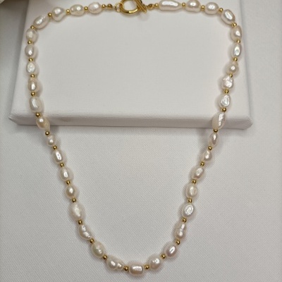 Colar de pérolas brancas e contas douradas sobre fundo branco