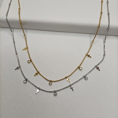 Colares dourado e prateado com pendentes de cruz e cristais sobre fundo branco