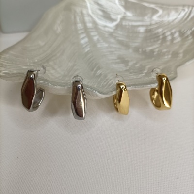 Quatro brincos tipo argola metálicos prateados e dourados sobre base de vidro ondulado.