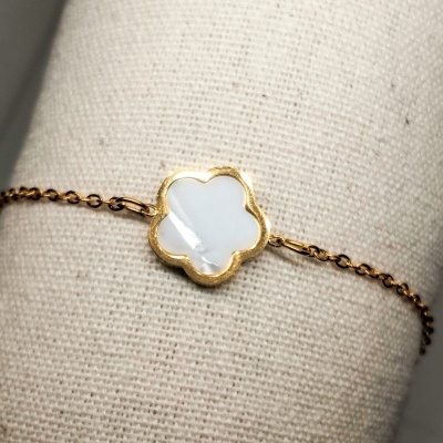 Pulseira dourada com pendente em forma de flor branco e dourado