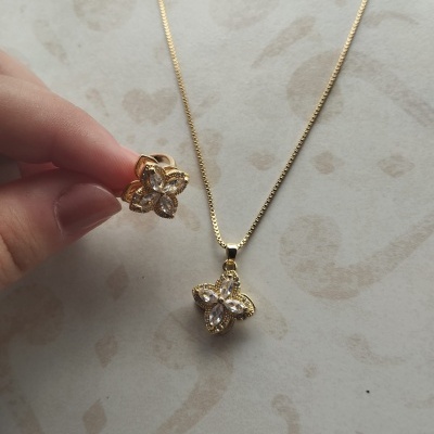 Anel e colar dourados com pendentes em forma de flor com pedras cristalinas