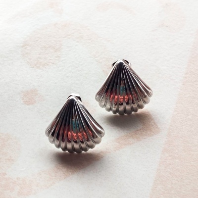 Brincos prateados em forma de concha com texturas em relevo