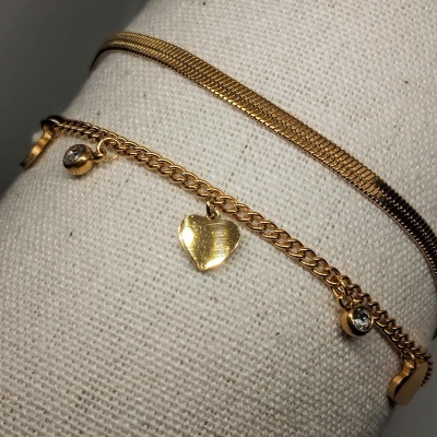 Dois braceletes dourados com design diferente sobre tecido bege