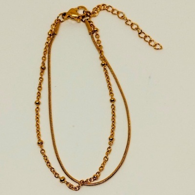 Pulseira dourada com duas correntes e fecho ajustável sobre fundo branco.