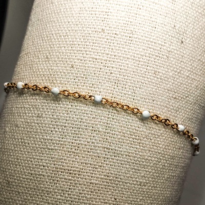 Pulseira dourada com pérolas em suporte de tecido bege