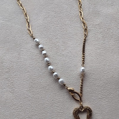 Colar dourado com pérolas e pendente de coração sobre fundo branco