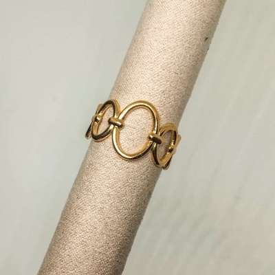 Anel dourado de design circular sobre suporte de tecido bege