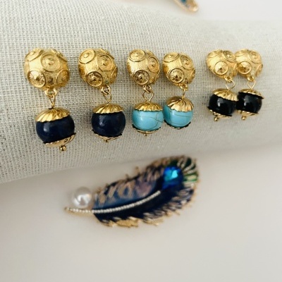Brincos dourados com pedras azuis e broche de pena azul