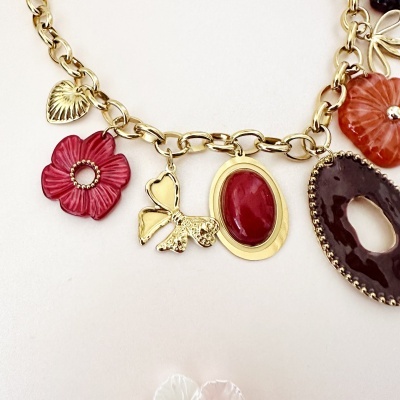 Colar com pendentes decorativos em forma de flor, borboleta e pedras coloridas em fundo branco