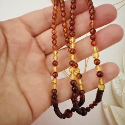 Colar de contas redondas âmbar em mão com fundo branco