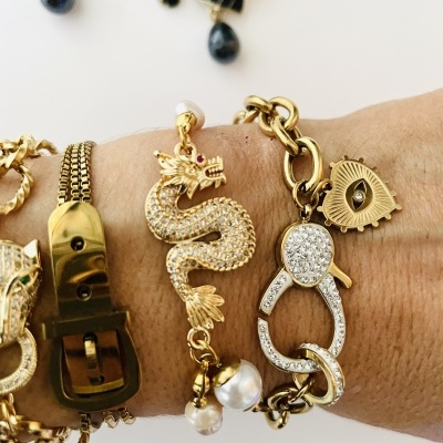 Três pulseiras douradas com detalhes diferentes usadas no pulso