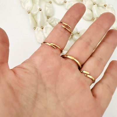 Mão com anéis dourados e colar de pérolas brancas em fundo branco