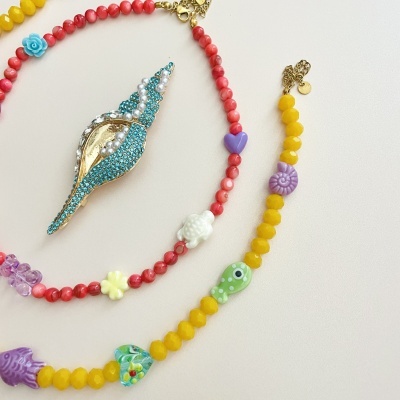 Colares coloridos com contas e um pingente de concha decorado com pedras azuis e pérolas