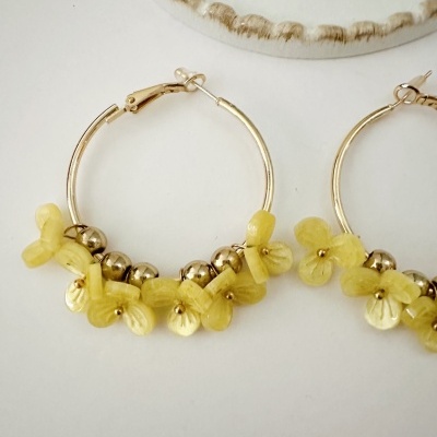 Brincos de argola dourados com flores amarelas e contas metálicas