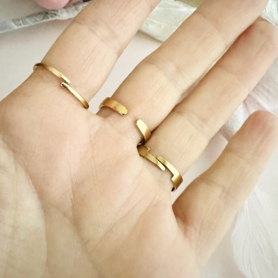 Três anéis dourados abertos numa mão humana.