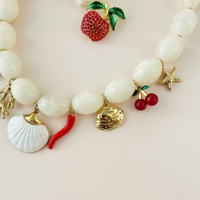Colar com contas brancas e vários pendentes decorativos coloridos e dourados
