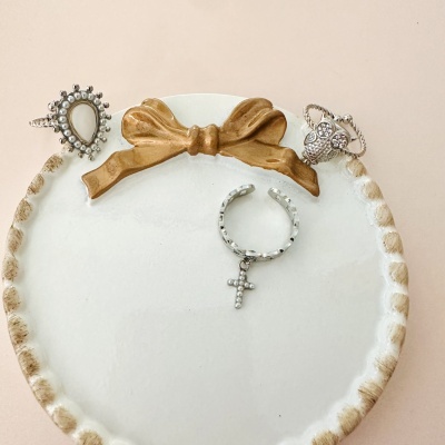 Três anéis prateados com pérolas e pedras em base branca com laço castanho