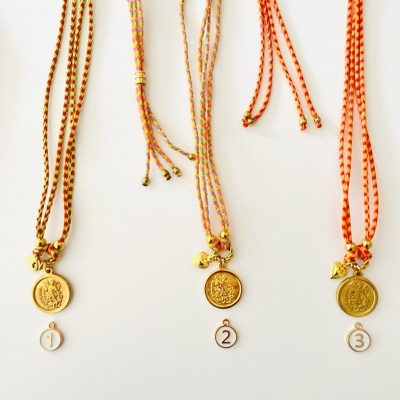 Três colares com pendentes dourados e cordões coloridos numerados de 1 a 3