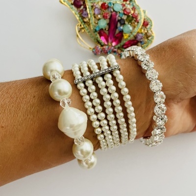 Pulseiras de pérolas e cristais com broche colorido em formato de asa