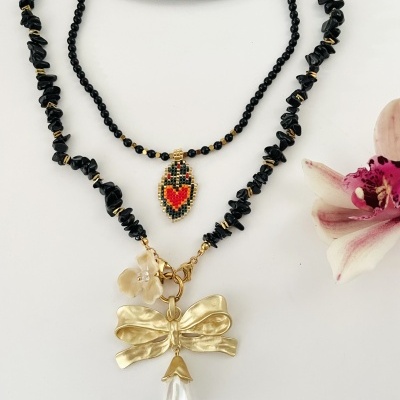 Dois colares com pendentes, um com coração bordado e outro com laço dourado e pérola falsa