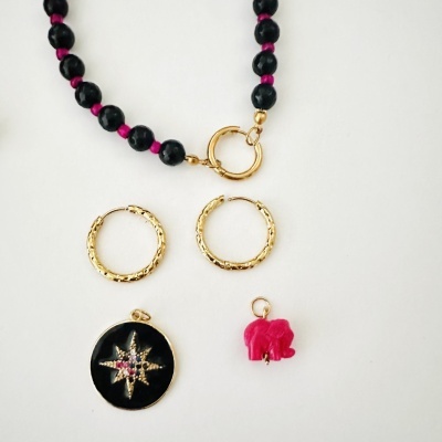 colar de contas pretas, brincos de argola dourados, medalha preta com estrela dourada e pedras, pendente rosa elefante