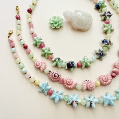 Colares coloridos com contas de estrela, caracol e esfera, com figuras decorativas de flor verde e tartaruga branca.