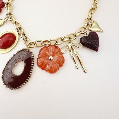 Colar dourado com vários pendentes coloridos sobre fundo branco