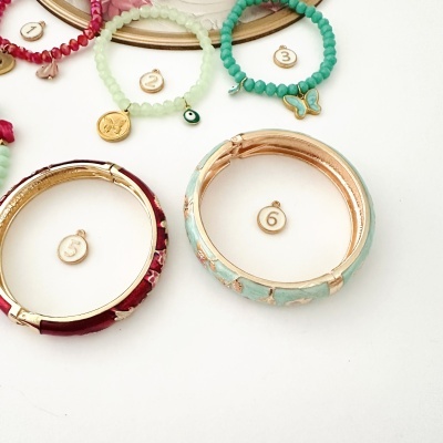 Pulseiras coloridas com pingentes em fundo branco e etiquetas numeradas