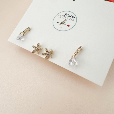 Conjunto de brincos dourados com pedras transparentes em cartão com logótipo Martin Cotovia