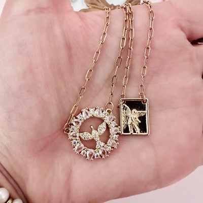 Colar dourado com pendentes de anjo e pedras em mão