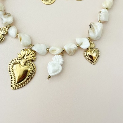 Conjunto de colar e brincos dourados e brancos com pendentes em formato de coração