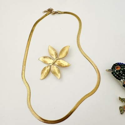 Colar dourado e flor dourada com textura sobre fundo branco