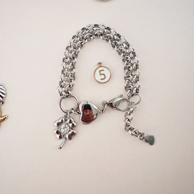 Pulseira prata com três pendentes sobre fundo branco