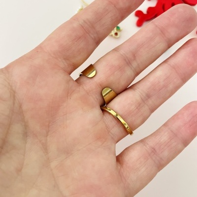 Mão com dois anéis dourados e pendentes coloridos ao fundo