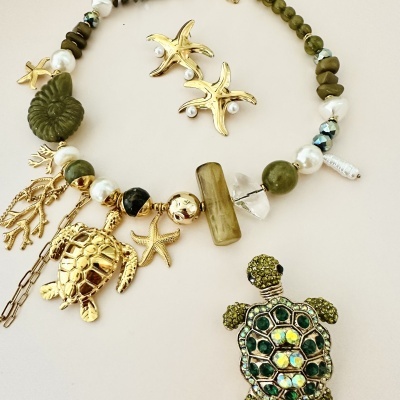 Conjunto de colar e brincos com figuras marinhas douradas e pedras verdes e brancas